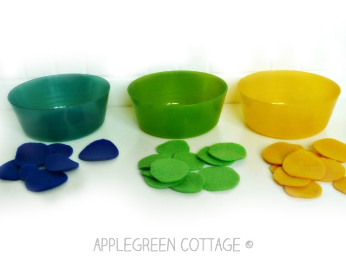 felt scraps cut into circles in three colors with plastic bowls in matching colors ready for play