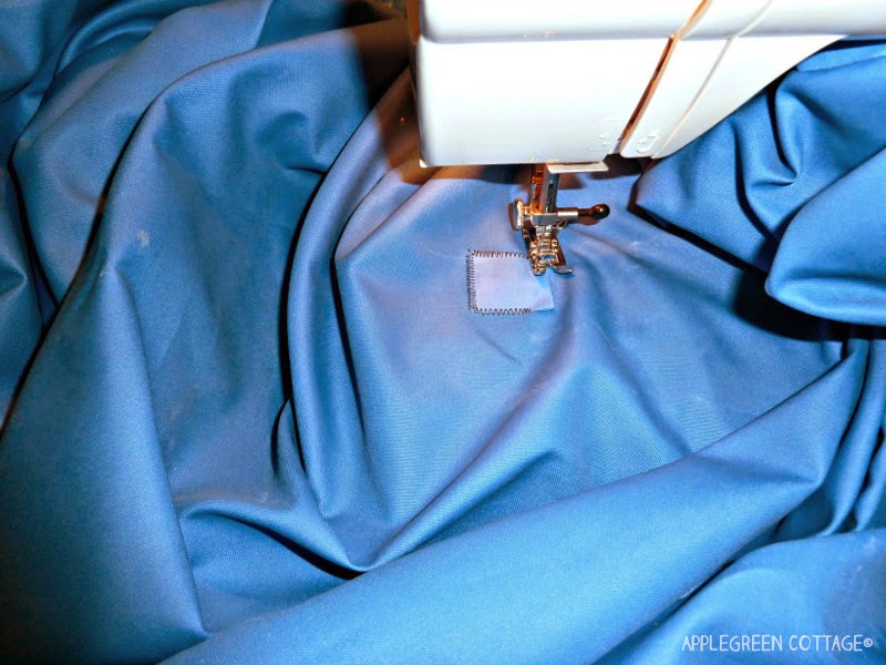 blue shade sail fabric being repaired using a sewing machine 