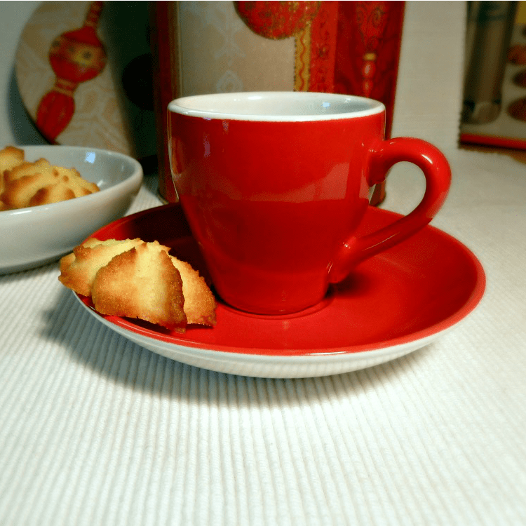 red coffee cup with a coconut cookie on a plate