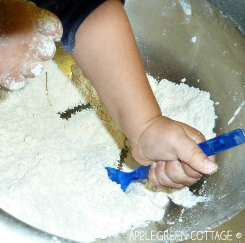toddler hands playing with flour