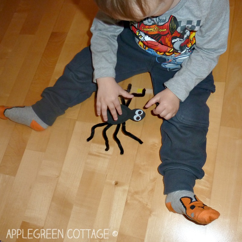 sitting kid playing with a finished pipe cleaners spider