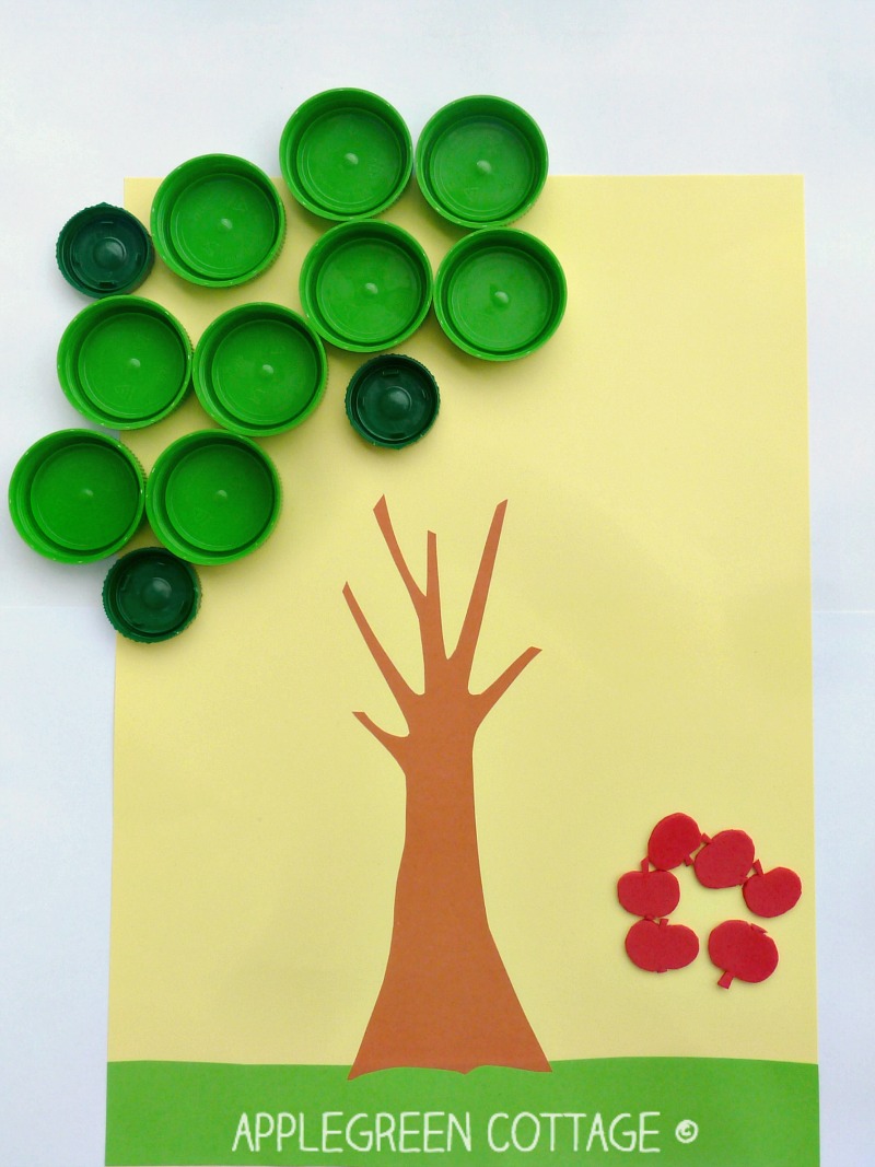 homemade materials and botrtle caps with a tree trunk drawing, ready to play an apple search counting activity for kids