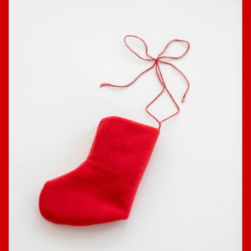 Small red fleece stocking ornament with simple curved seams and a thread loop, ideal for quick holiday sewing.