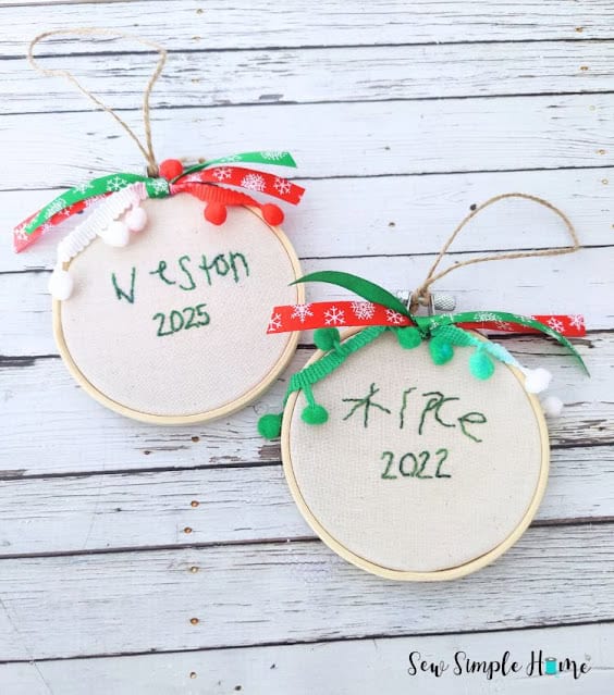 Kids’ handwriting hand embroidered in a small hoop ornament with festive ribbons and pom pom trim.