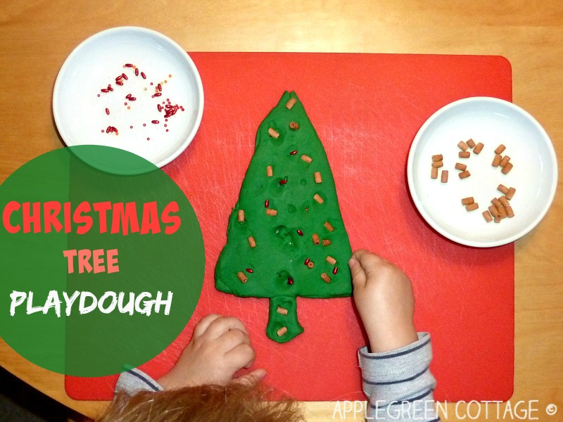 a kid's hands modelling playdough into a christmas tree, on a red plastic tray