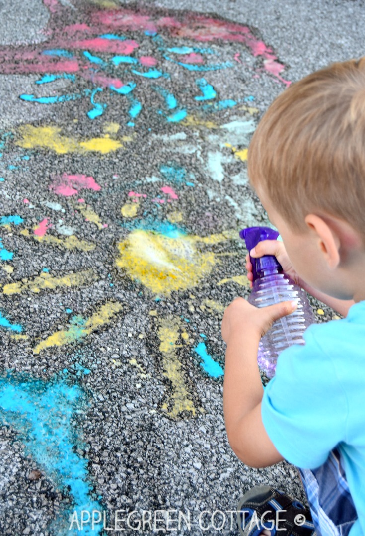 a child spraying over a fizzing colored drawing