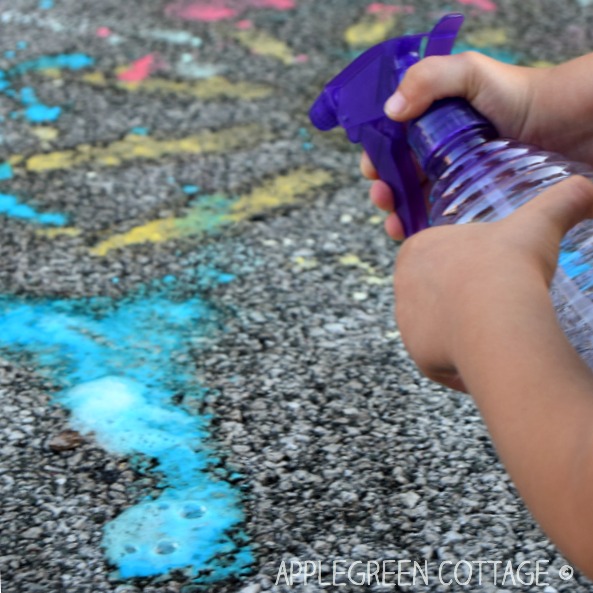 a kid playing with fizzing colored water on a sidewalk