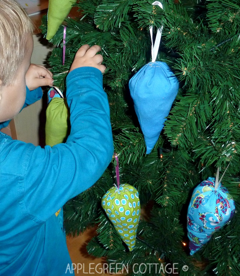 a kid decorating a christmas tree with handmade ornaments