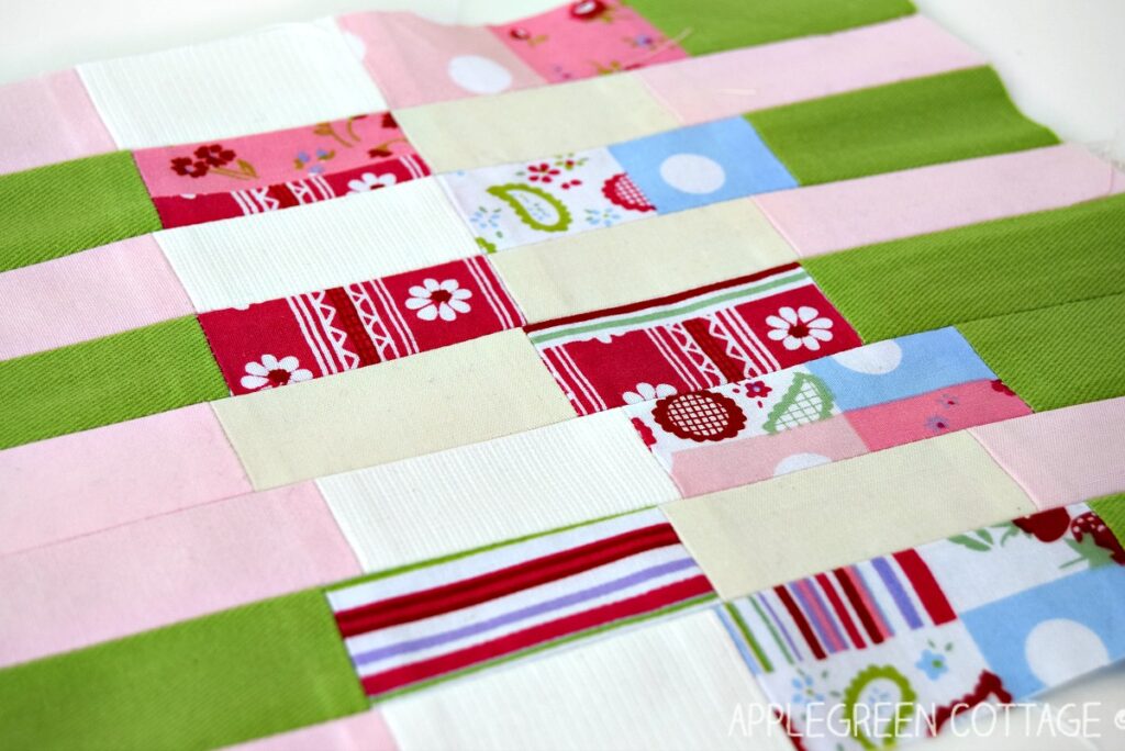 a semi-finished patchwork made out of fabric scraps in white, green, and pink