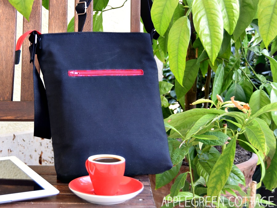 black diy ipad bag on a bench with greenery as backdrop and a red cup with cappucino 