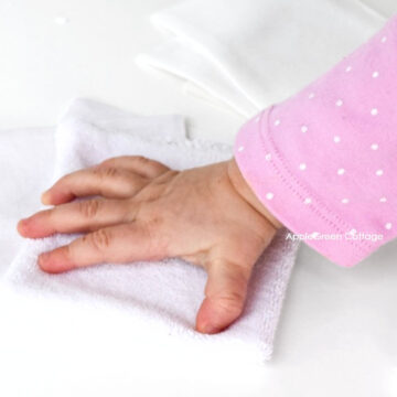 A baby hand holding a homemade fabric tactile toy.