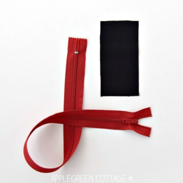 a red zipper with a piece of black fabric next to it to create a zipper tab