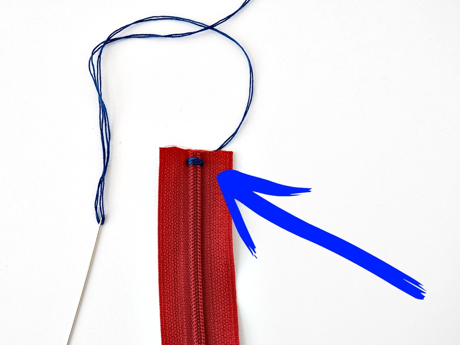 a red zipper cut on one end with the zipper end tacked with blue thread to prevent opening