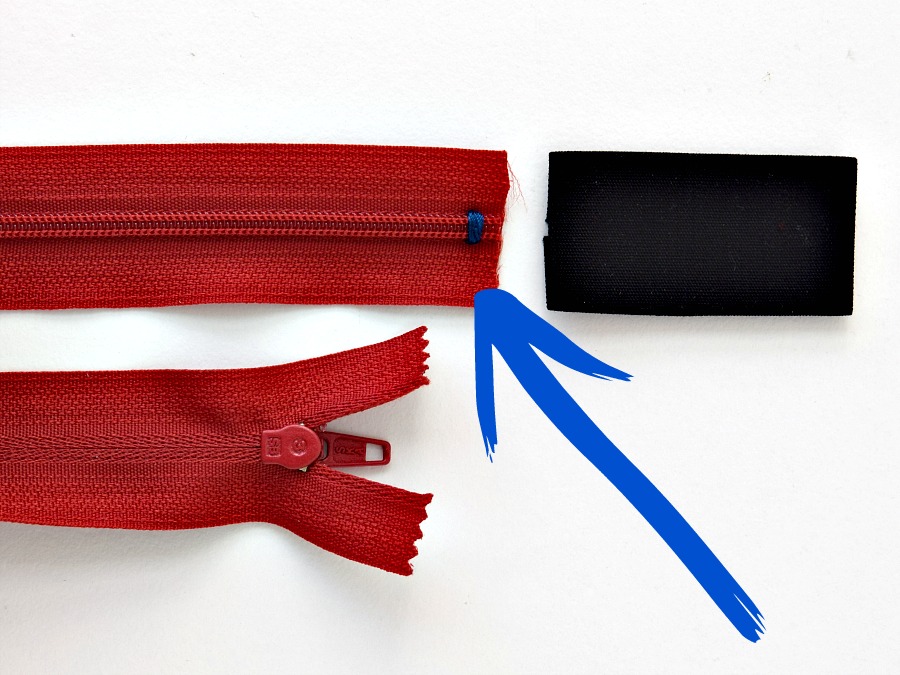 sewing zipper tab with two zipper ends shown next to a folded piece of fabric for a zipper tab