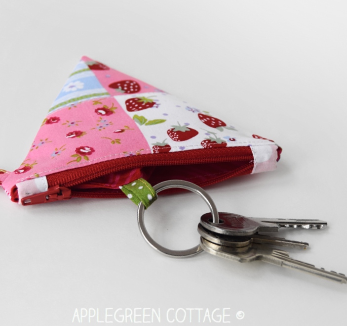 a flat coin purse with an open zipper that has fabric tabs
