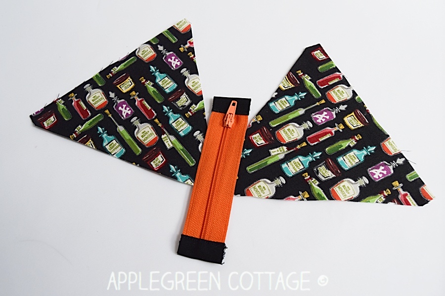 two pieces of halloween themed fabric and an orange zipper