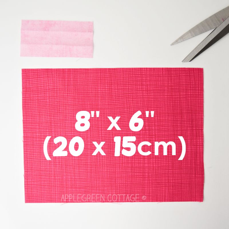 two rectangular pieces of fabric in pink 
 with measurements marked to sew a fabric bow