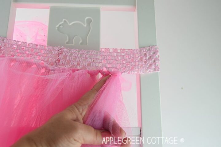 hand tying tulle strips on a crochet waistband, making a tulle skirt