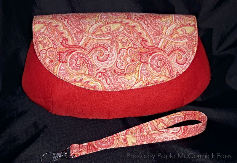 a handmade red curved clutch purse in a dark room