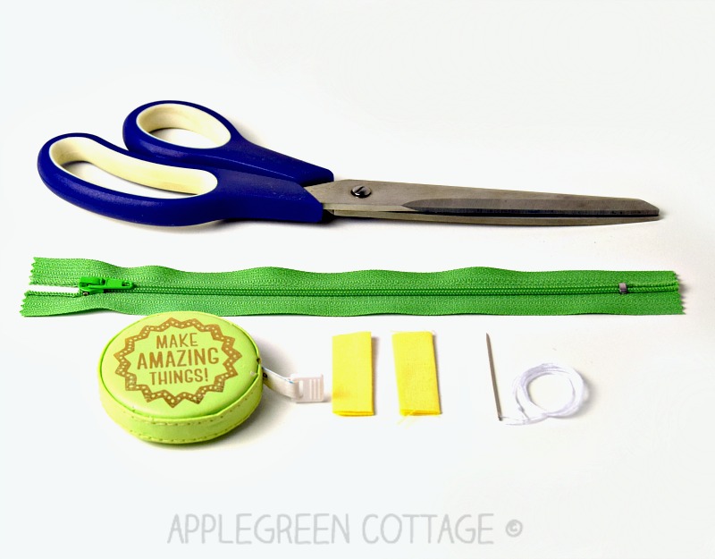 a new standard zipper , scissors, measuring tape, and two small pieces of fabric on a white surface