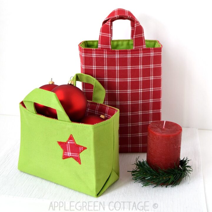 two finished handmade fabric gift bags on a holiday themed table.