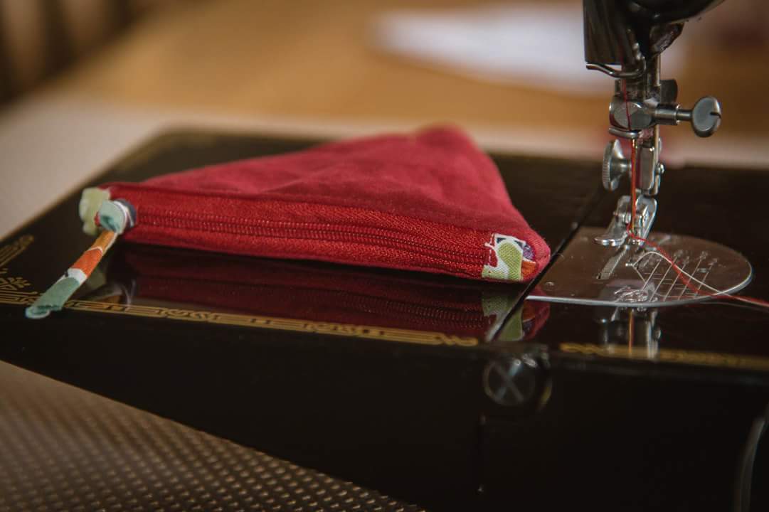 a finished small coin purse with a ziper in red fabric on a sewing table