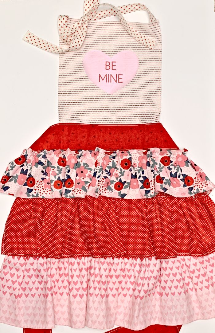 a homemade apron in white and red with a heart shaped applique