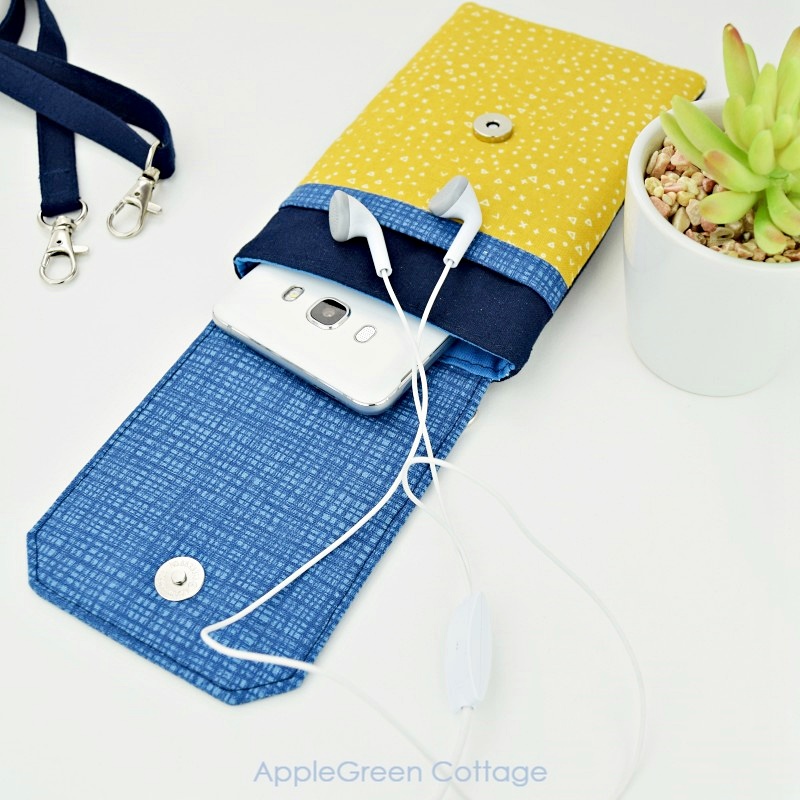 Crossbody cell phone pouch with headphones and a phone peeking out