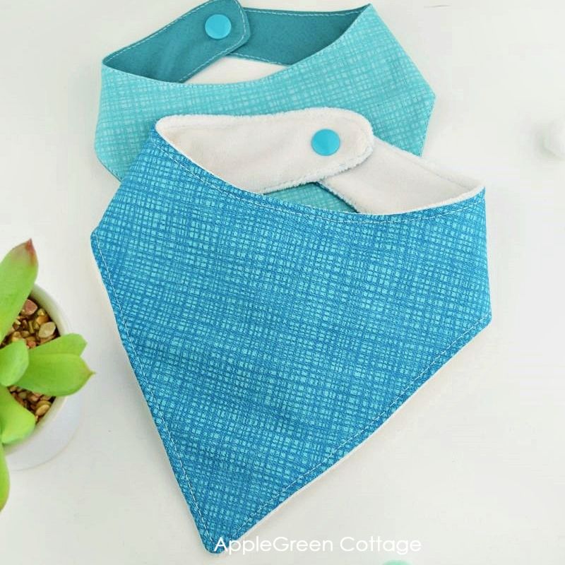 two fabric bandana bibs in two sizes and two shades of blue textured prints