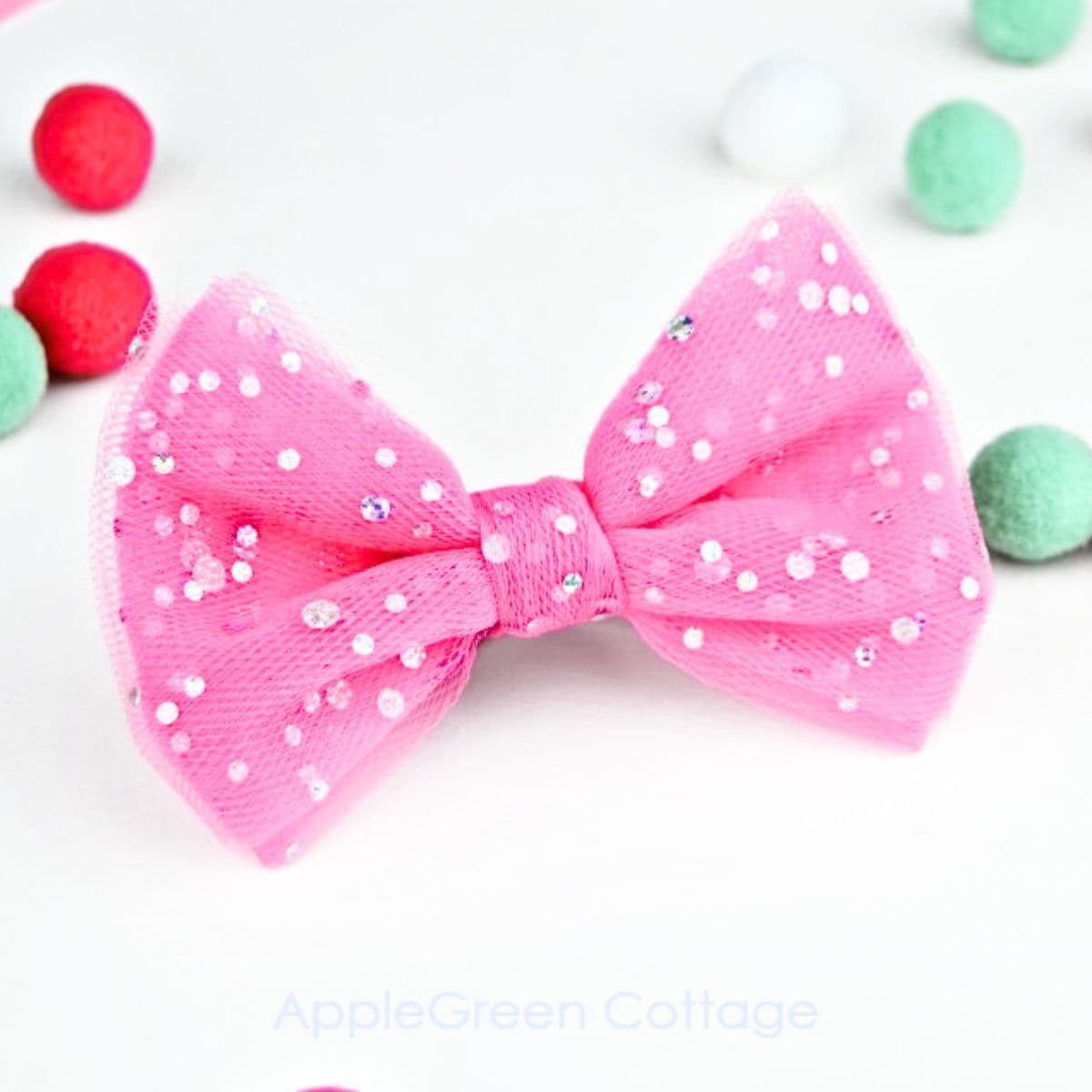 a finished glitter pink tulle bow with mint and pink and white pompoms