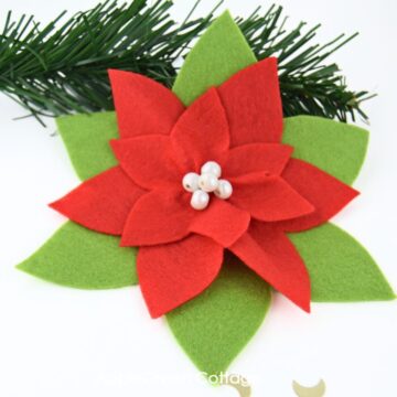 a handmade poinsettia ornament in red and green felt, with pearls attached to the middle