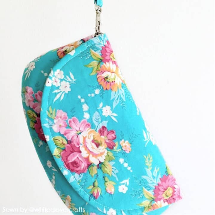 an elegant, small handmade fabric purse in blue floral cotton print with a flap and a wrist strap
