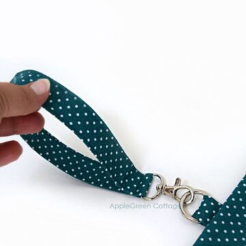 A hand holding a handmade wristlet strap sewn with cotton fabric.