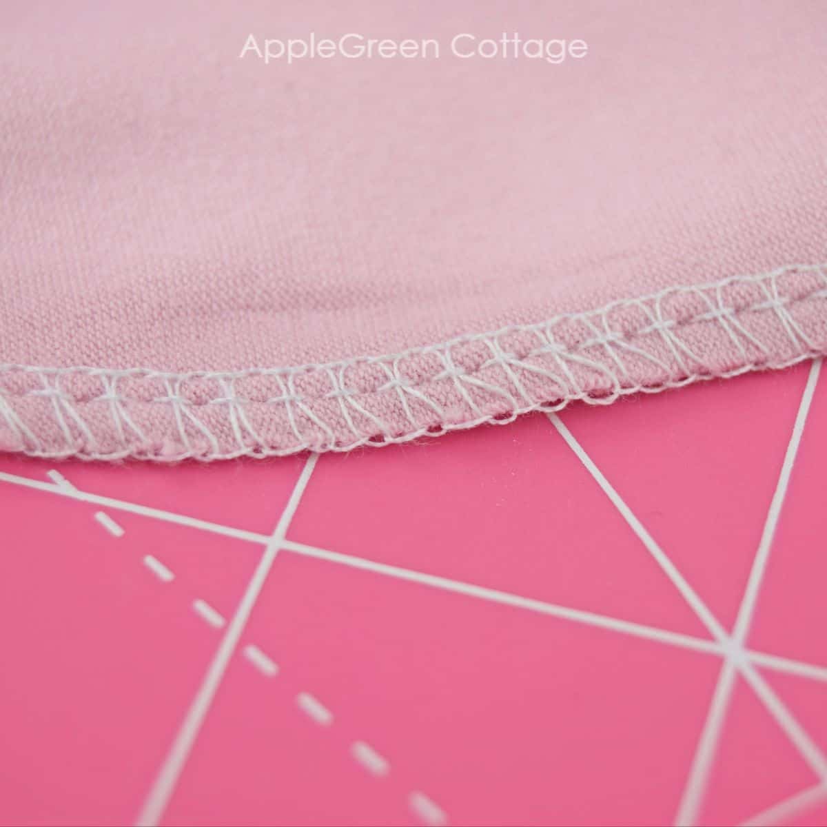 pink jersey with a serger seam on a pink cutting mat