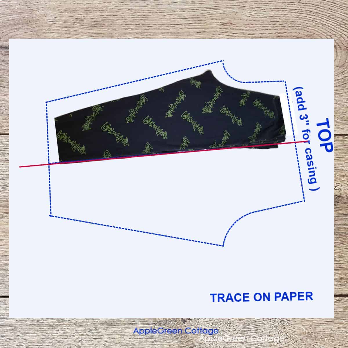 Tracing pajama pants pattern on paper using folded pants as a guide.