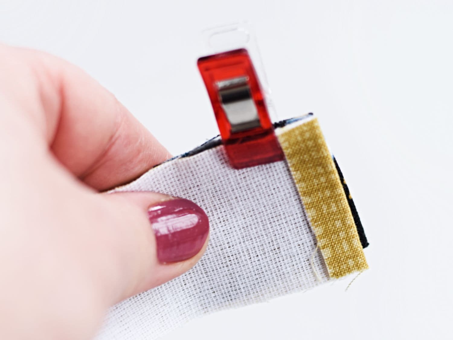 A hand holding two fabric pieces encasing the zipper tape, ready to sew a recessed zipper panel.