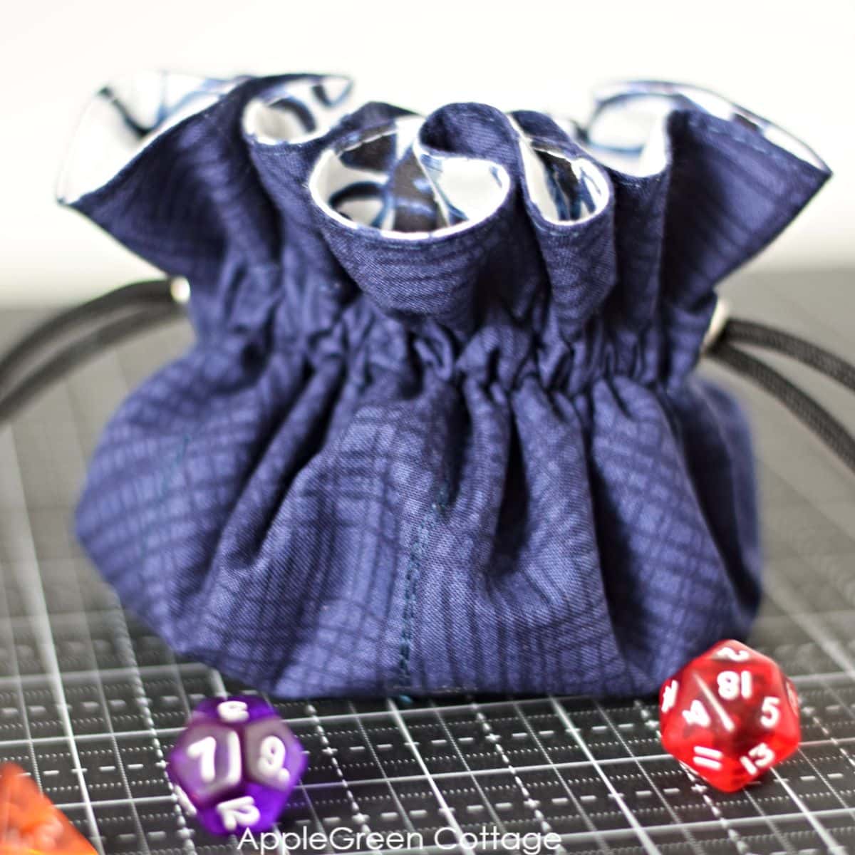 finished dice storage bag with polyhedral dice on a black surface