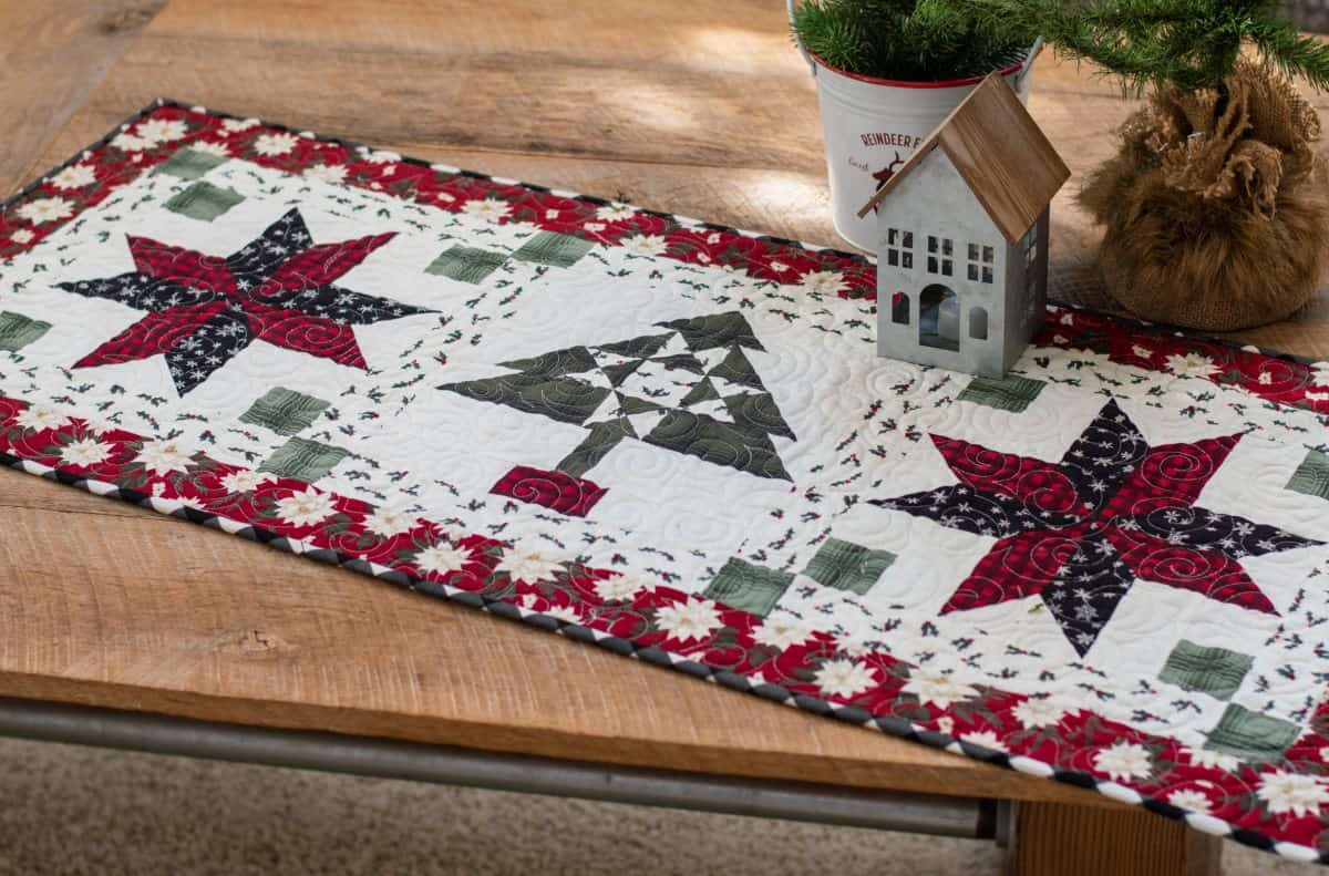 quilted table runner in white, dark red, and gray on a wooden table