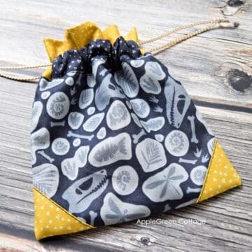 A finished fabric drawstring bag with ruffles and corner accents, sewn with applegreencottage pattern.