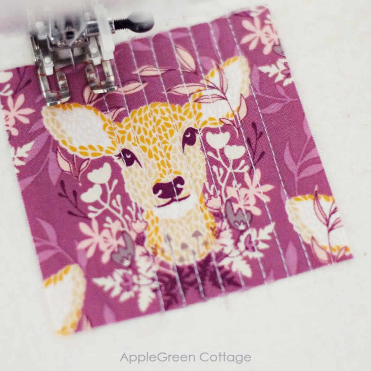 a scrap piece of fabric print showing a deer and sewn to quilt batting using a walking foot