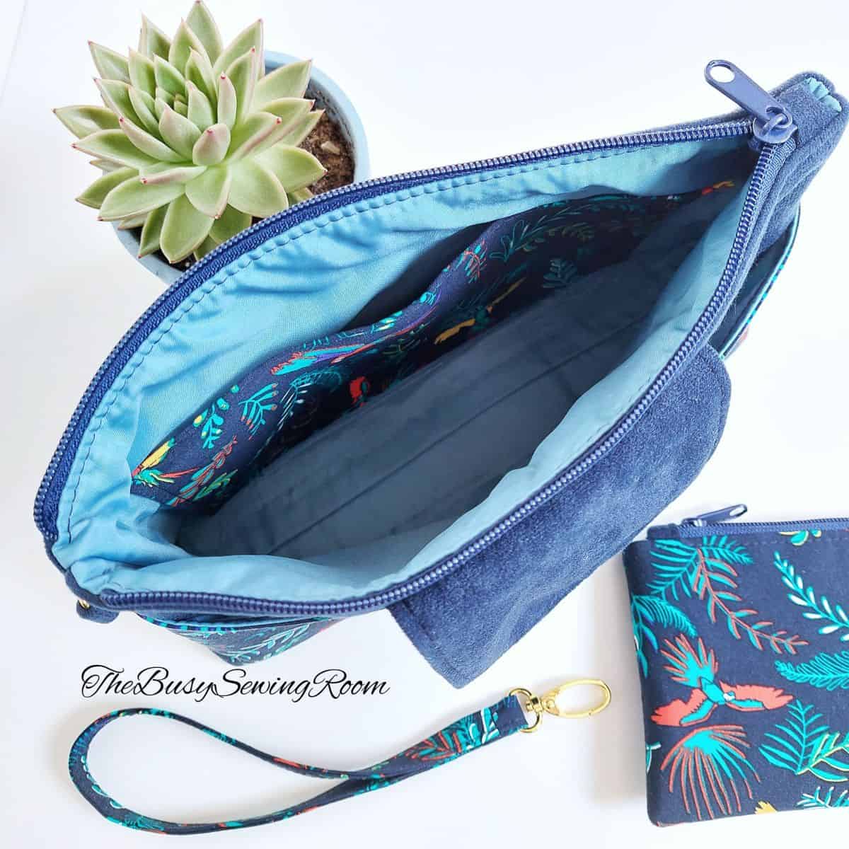 bird-eye's view of a blue cosmetic pouch wide open, with a small fabric pouch close by