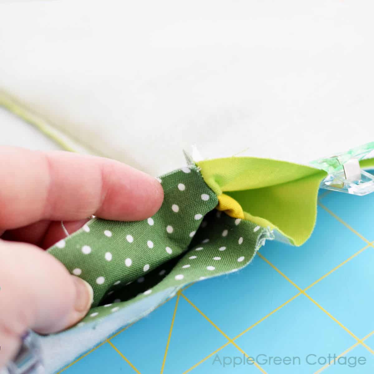 a closeup of a semi-finished zipper pouch with a hand holding the fabric