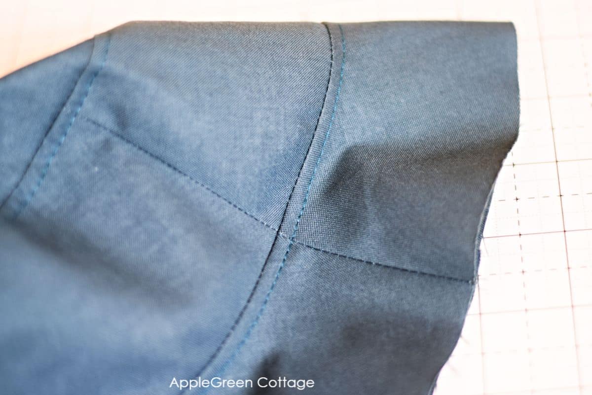 topstitching seams shown on a blue fabric hat with cutting mat in the background