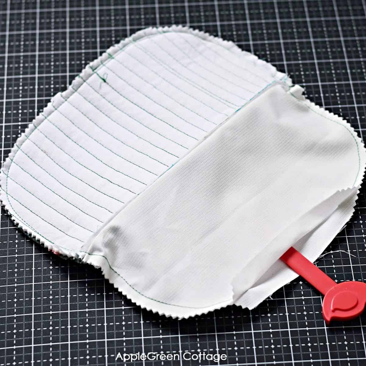 a white zipper pouch being sewn together and placed on a black cutting mat