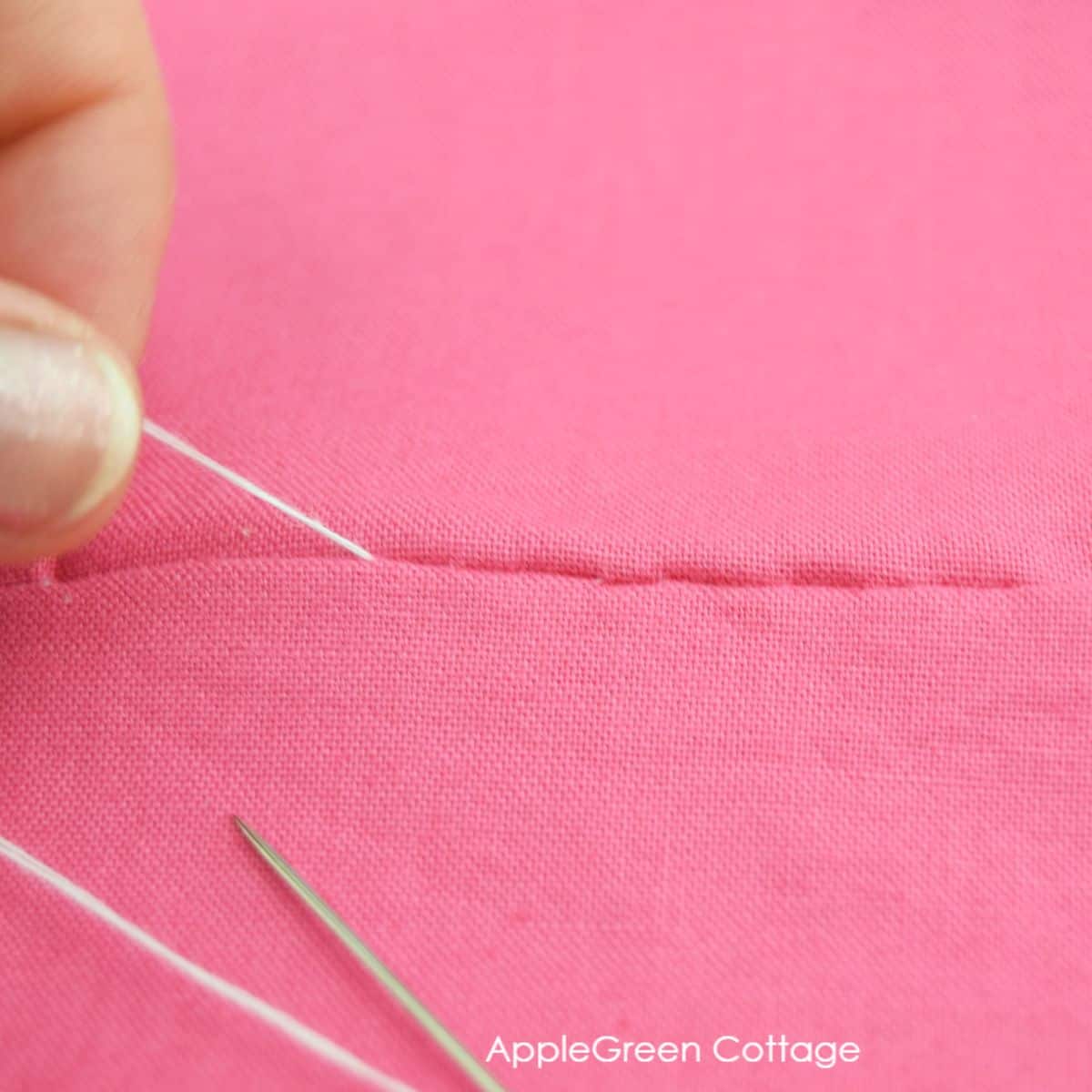 hand pulling on the thread with a finished invisible stitching