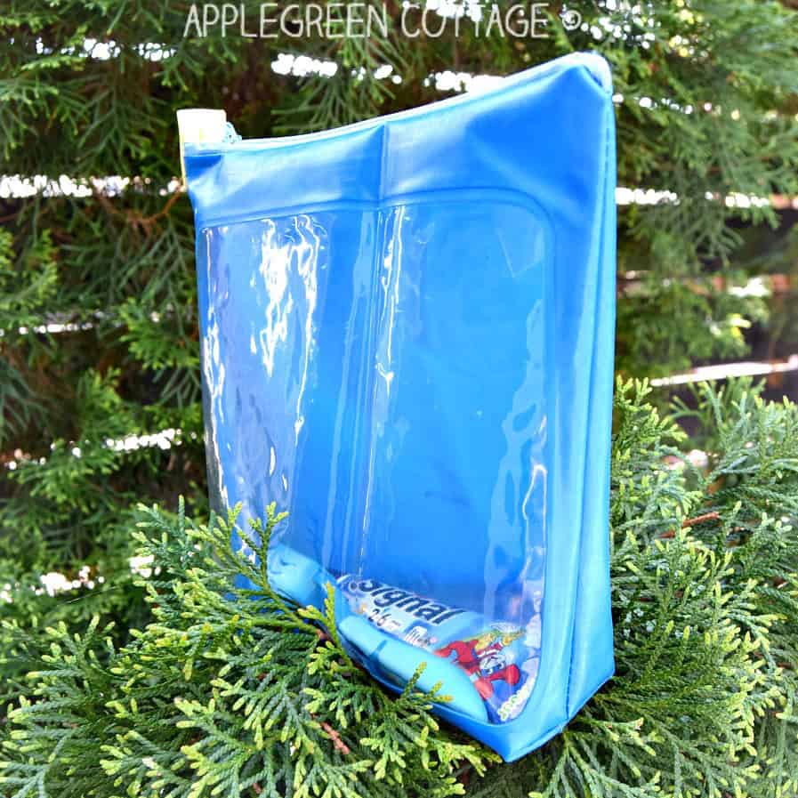 a zippered blue toiletry pouch with a transparent window, with a toothpaste and a toothbrush