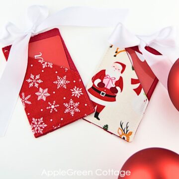 two finished handmade gift card holders made with christmas themed red and white fabric and a beautiful white ribbon bow