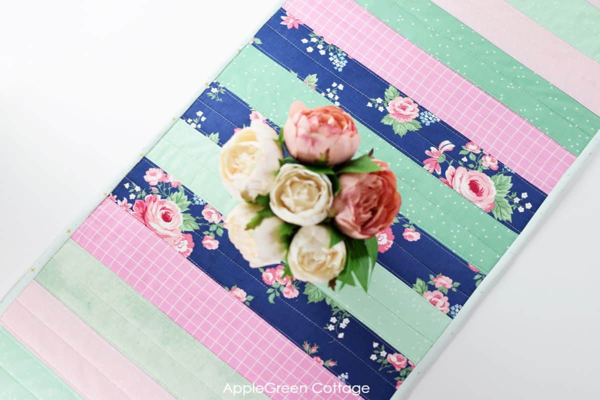 finished quilted table runner on a table setting with flowers