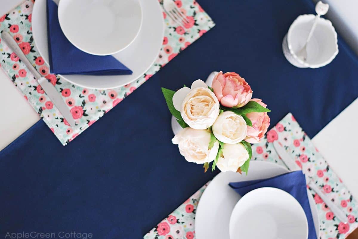 finished homemade table runner in blue solid home decor weight fabric on a table setting with floral placemats