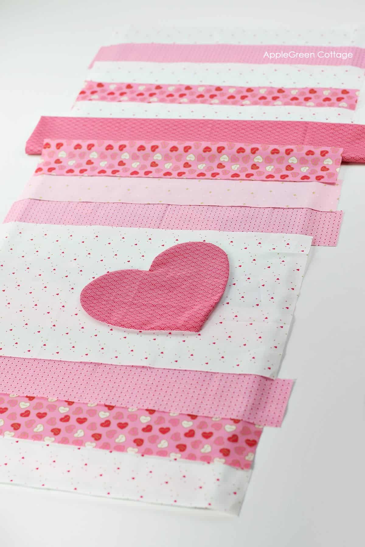 DIY quilted table runner with heart applique in pink, red, and white fabric